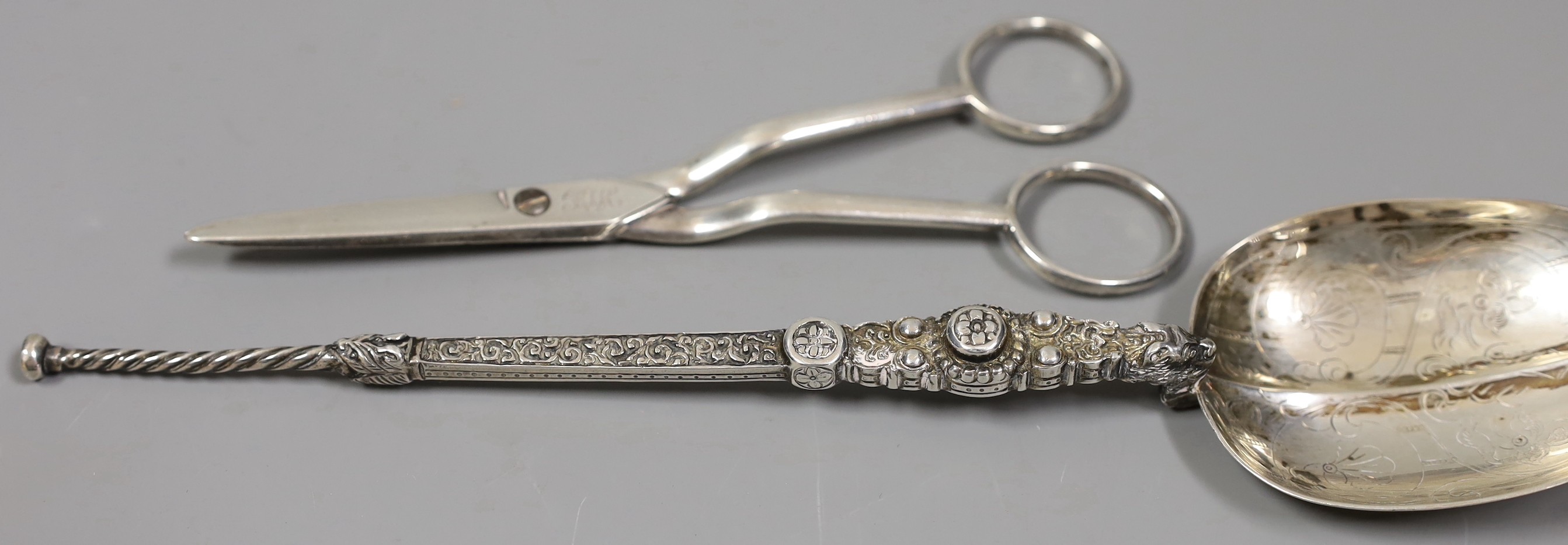 Pair of George III silver grape scissors, by Eley & Fearn, London, 1818 and a George V silver replica of the anointing spoon, Goldsmiths & Silversmiths Co Ltd, London 1910, 166 grams.